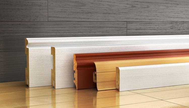 Assorted baseboards in different colors and finishes displayed on a wooden floor.