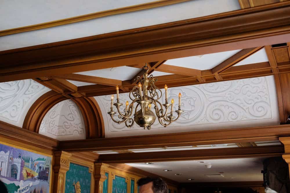An ornately decorated ceiling with wooden beams and a brass chandelier.