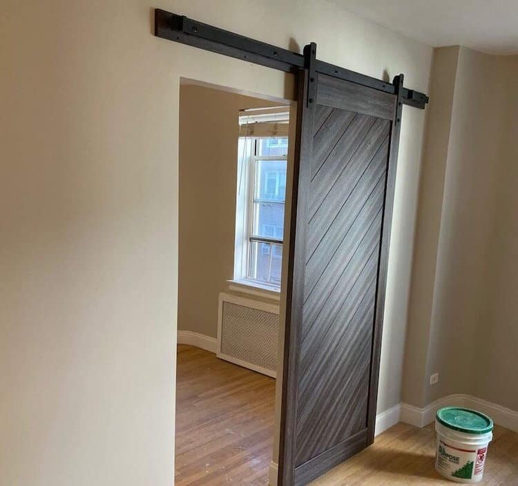 A sliding barn door with a wooden diagonal panel design installed in an interior doorway.