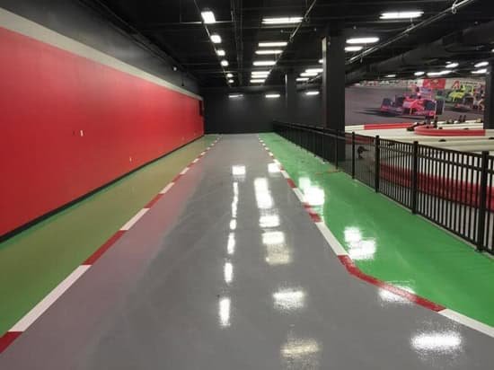 A polished indoor track with epoxy-coated flooring, featuring red, green, and gray sections with a glossy finish.