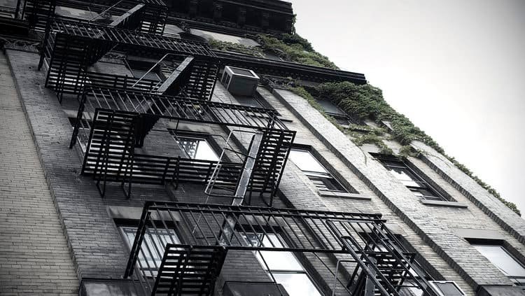 A black-and-white photo of a building with black-painted fire escapes.