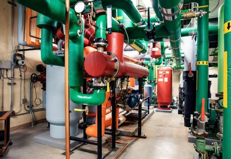 A mechanical room with brightly painted pipes in green, red, and orange, highlighting the organized and vibrant environment.